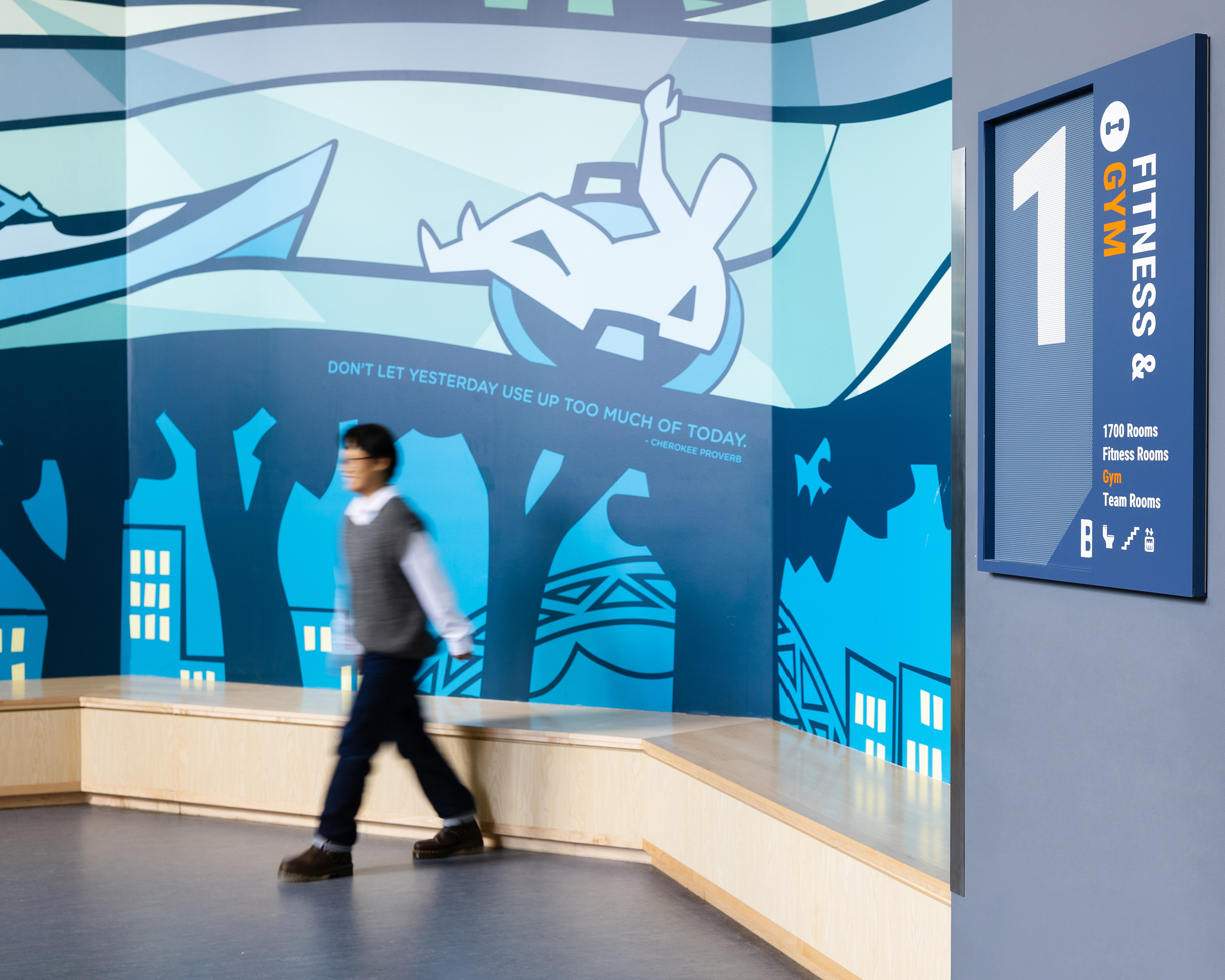 A person walks in by a wall mural at Charlottesville Middle School with a floor number 1 sign to the right