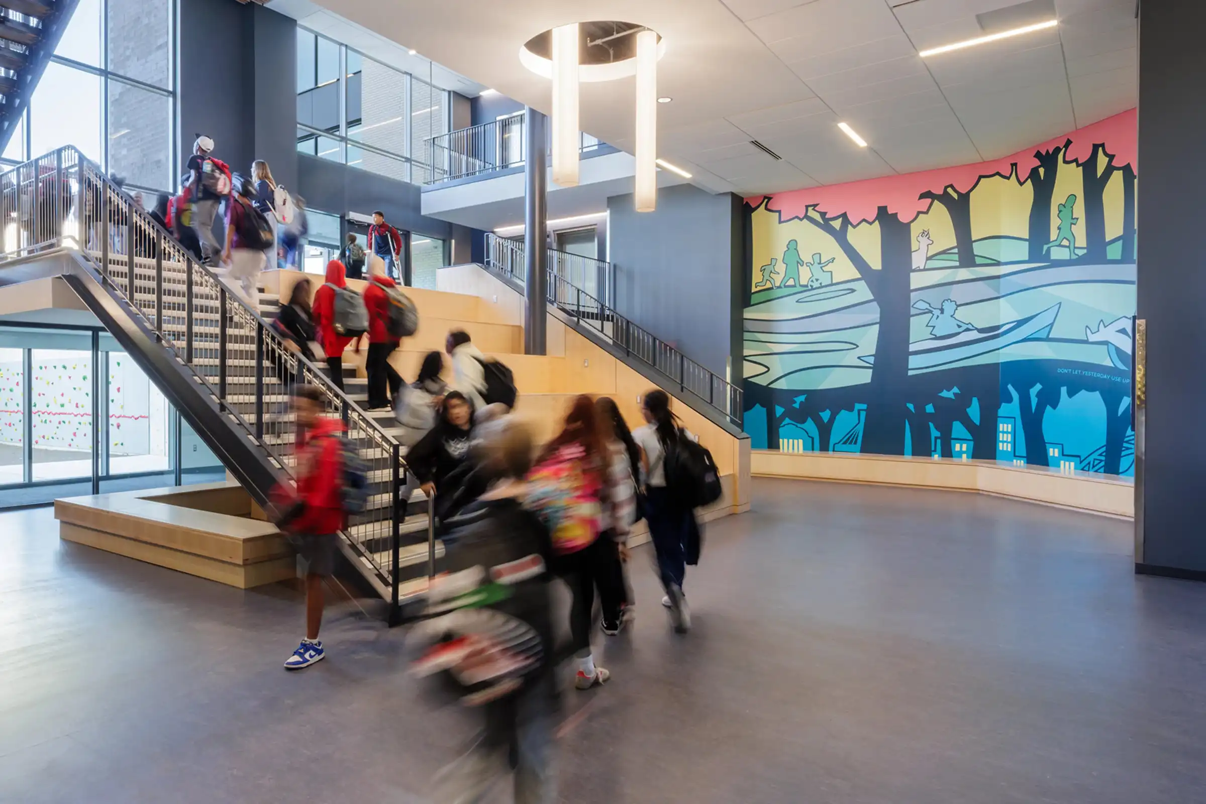 Students at Charlottesville Middle School take the stairs in front of a wall mural