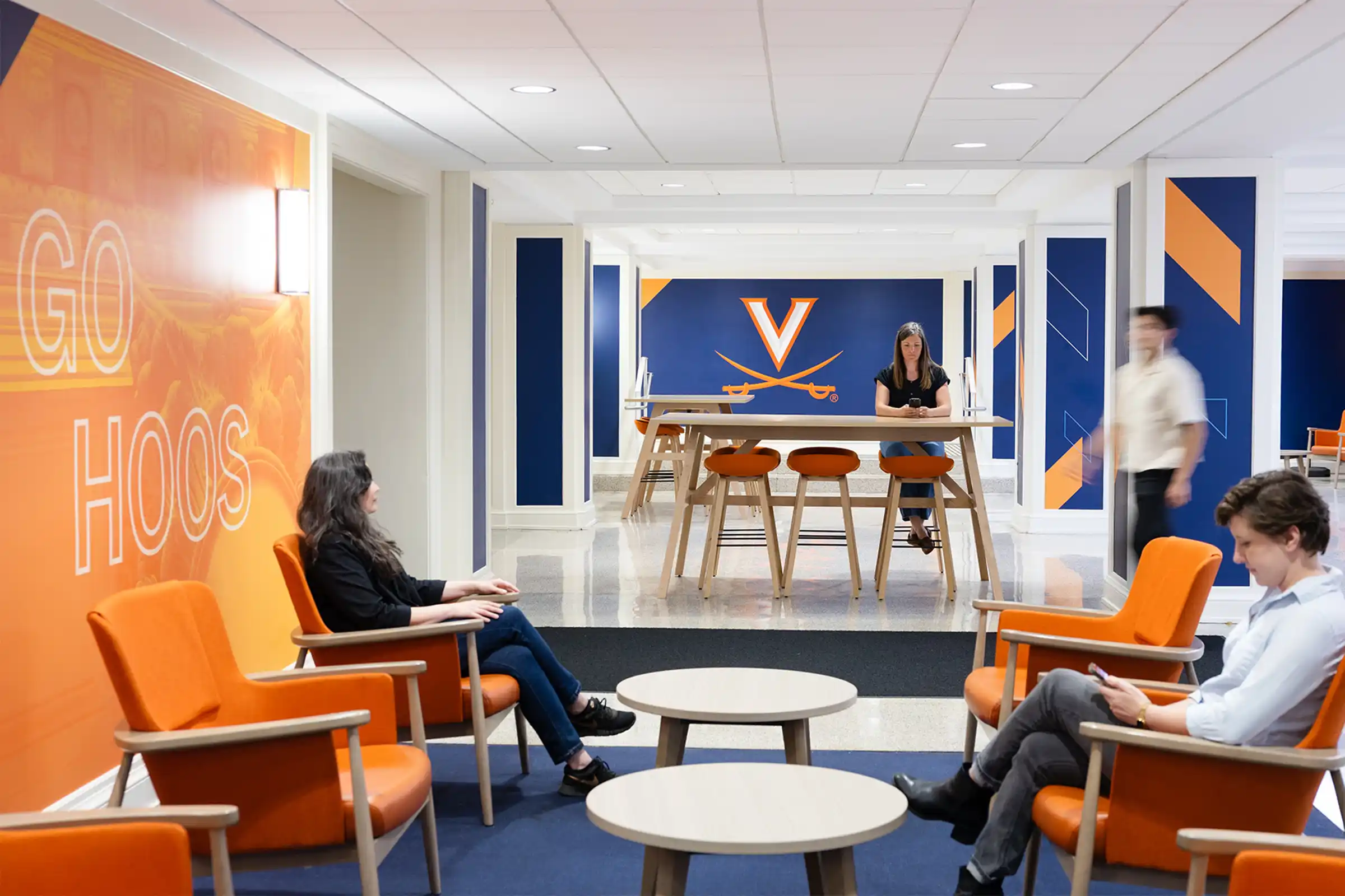 People sitting in a common area at Newcomb Hall with UVA colors and logos on the walls