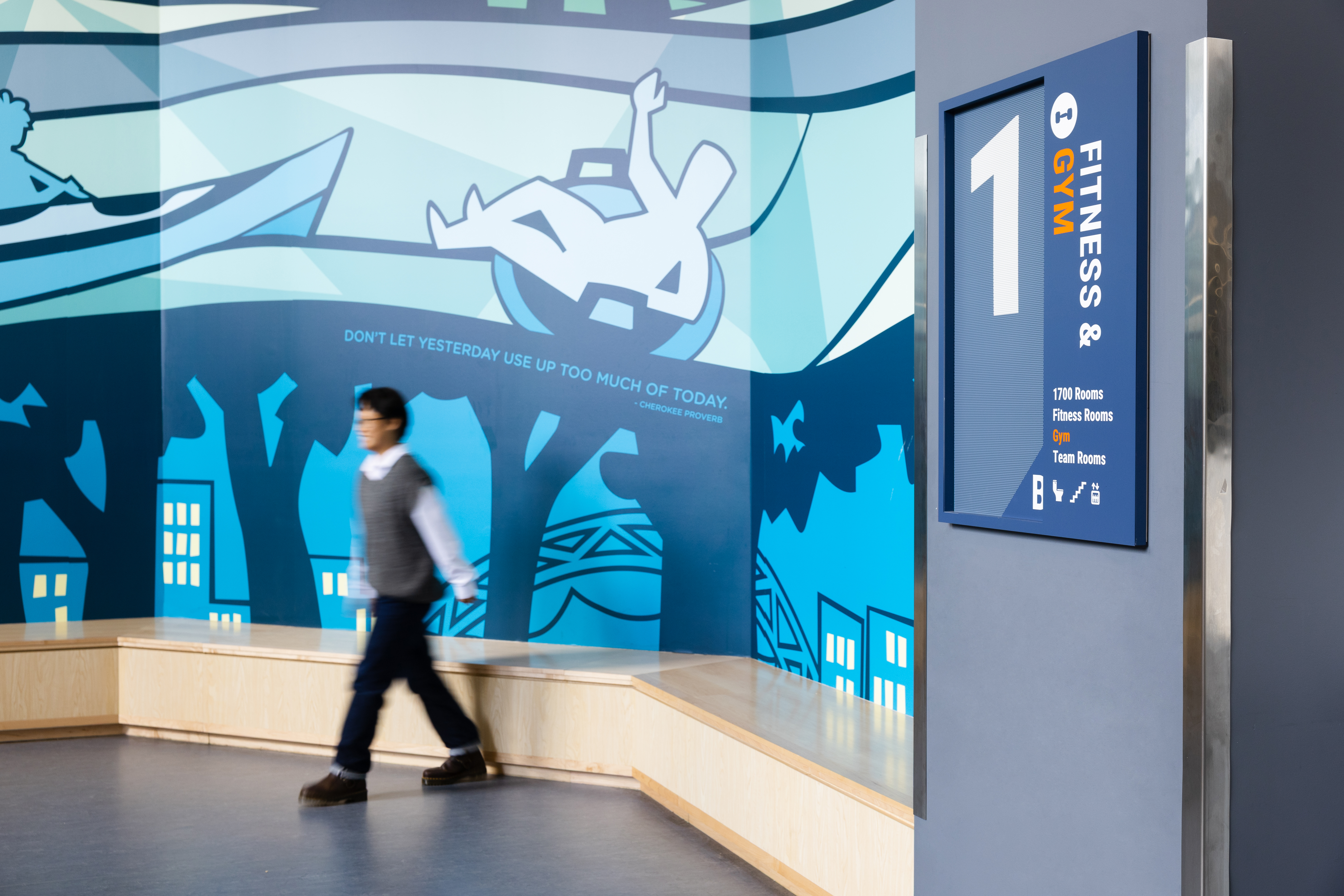 A person walks in by a wall mural at Charlottesville Middle School with a floor number 1 sign to the right