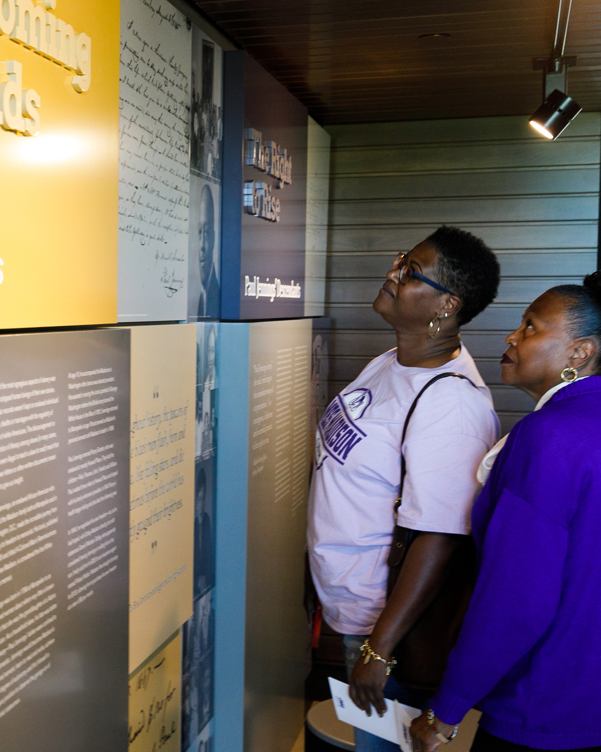 Two women read exhibit displays about Paul Jennings at Jennings Residence Hall