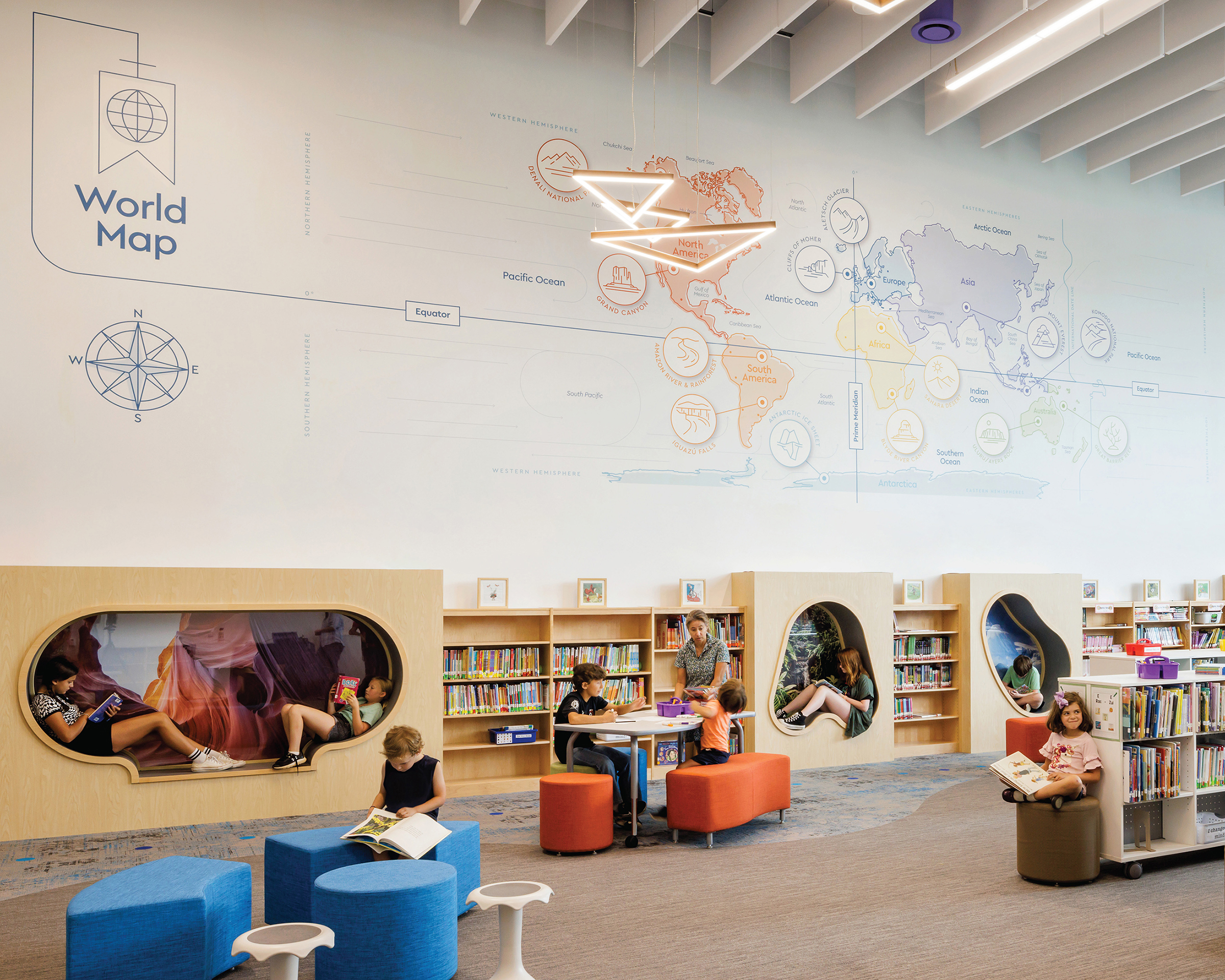 Children reading in front of wall graphics showing a world map in various colors at Cardinal Elementary School.