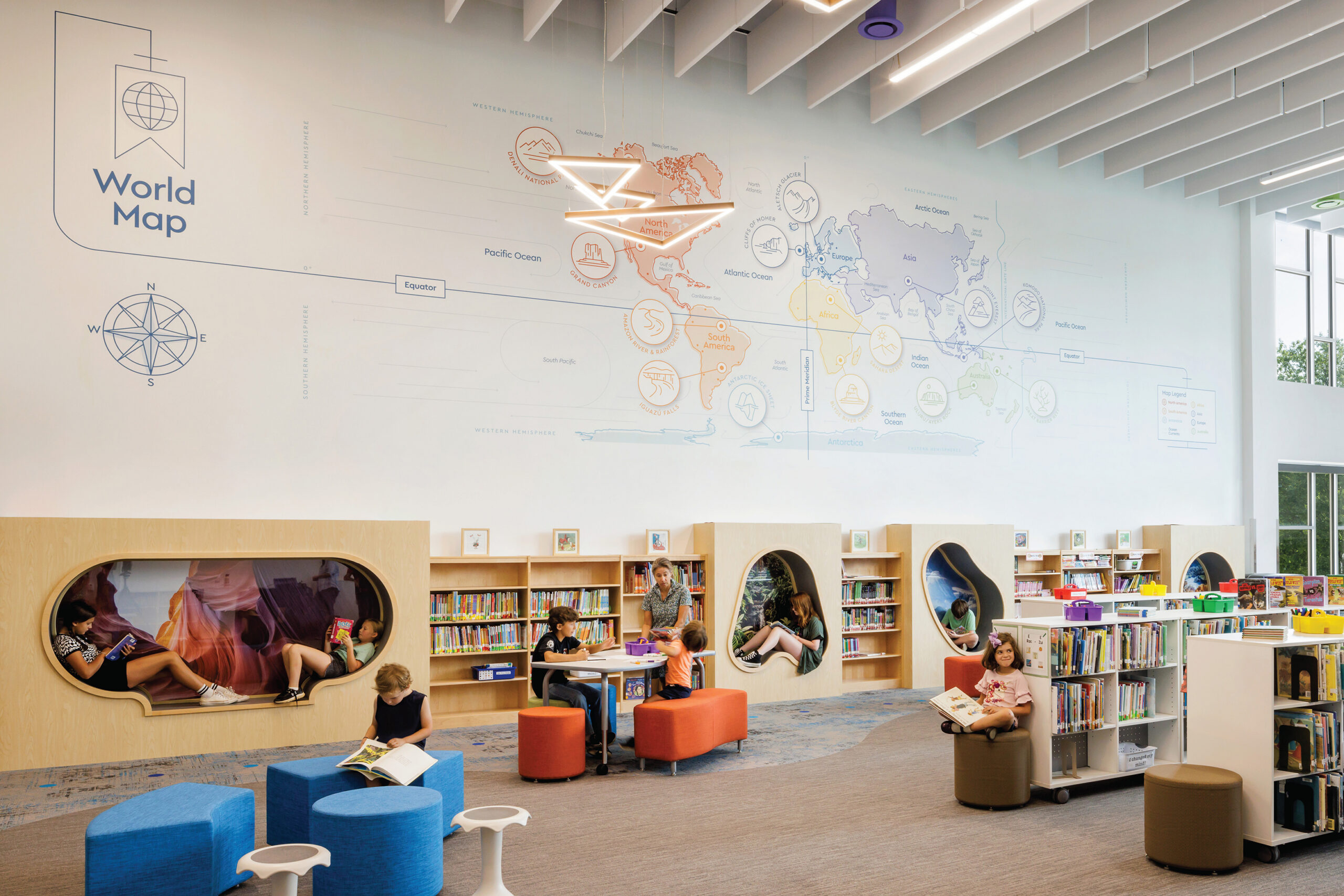 Children reading in front of wall graphics showing a world map in various colors at Cardinal Elementary School.