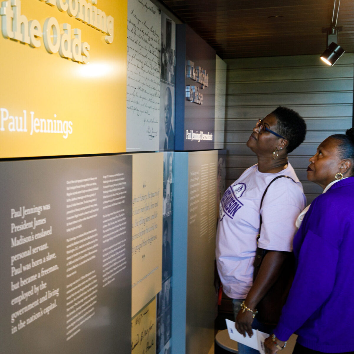 Two women read exhibit displays about Paul Jennings at Jennings Residence Hall