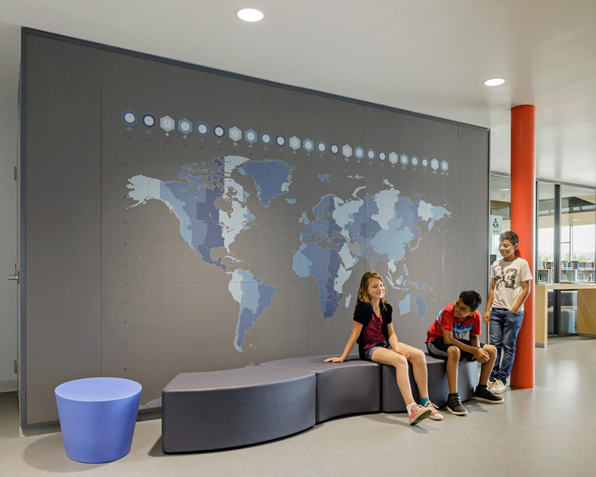 Children sit in front of a map wall graphic at Bluestone Elementary School