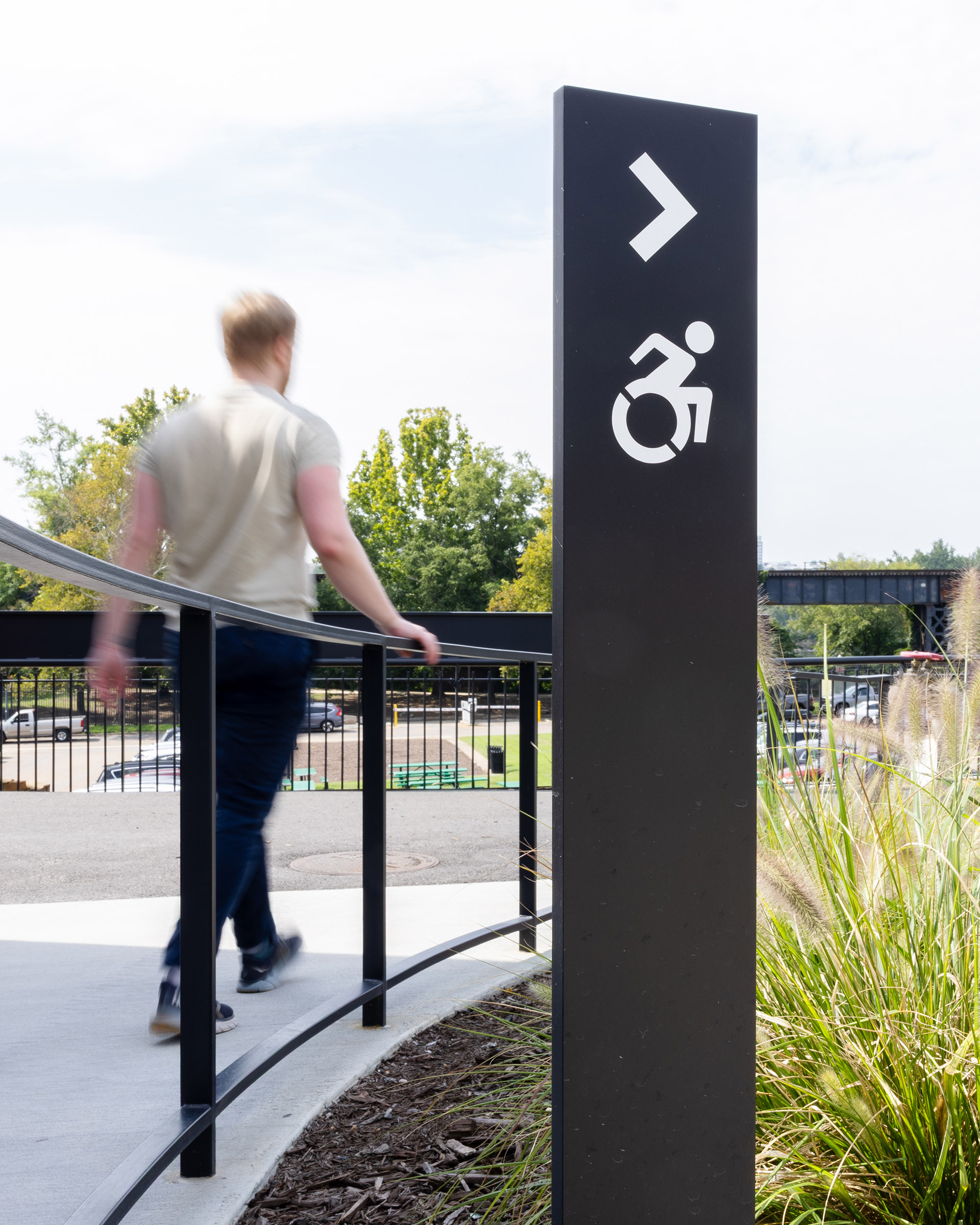 A man passes a directional sign guiding wheelchair users to a ramp at Allianz Amphitheater