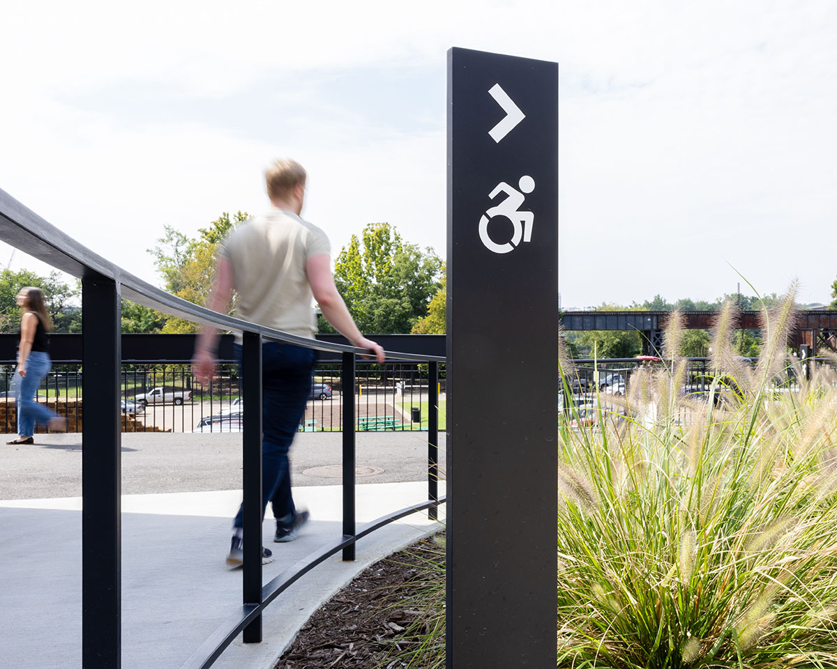 A man passes a directional sign guiding wheelchair users to a ramp at Allianz Amphitheater