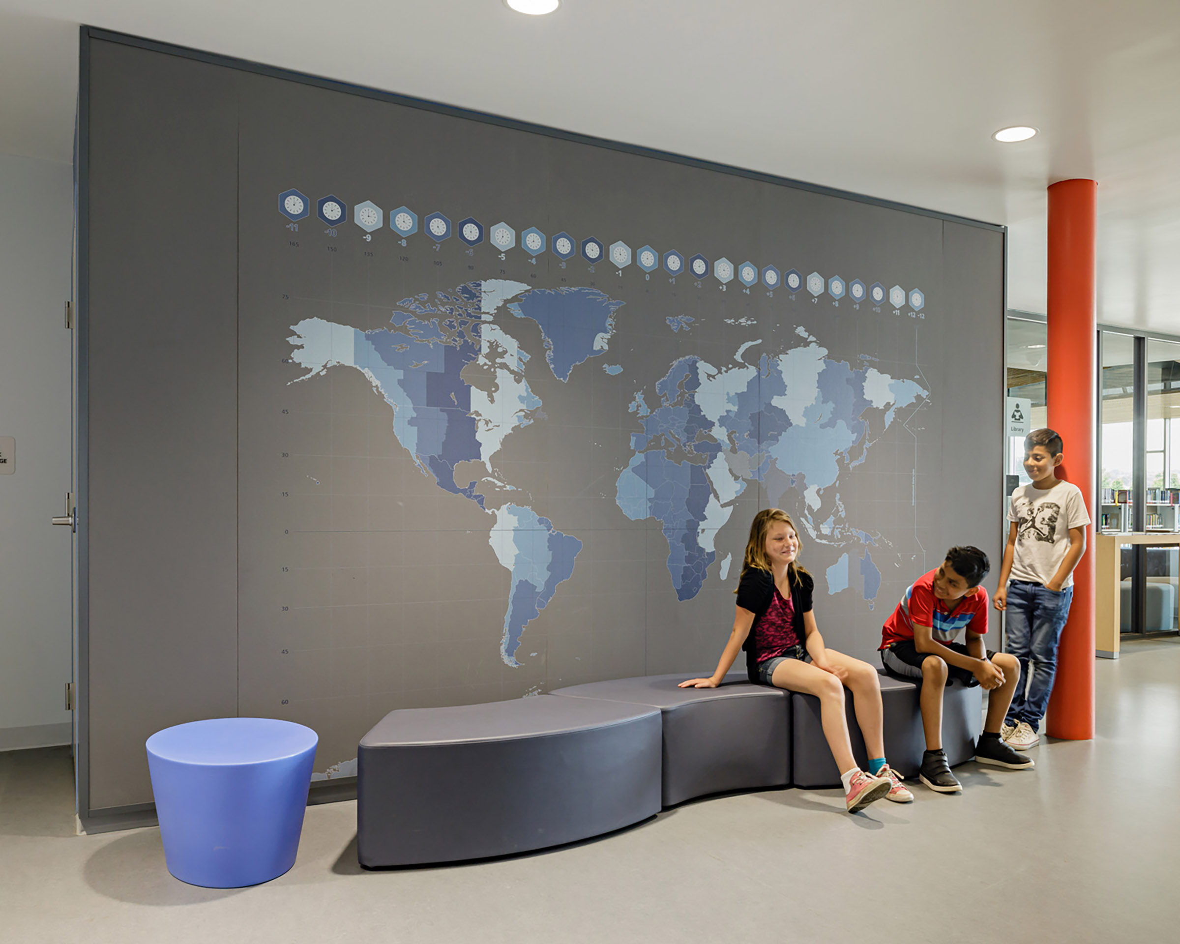 Children sit in front of a map wall graphic at Bluestone Elementary School