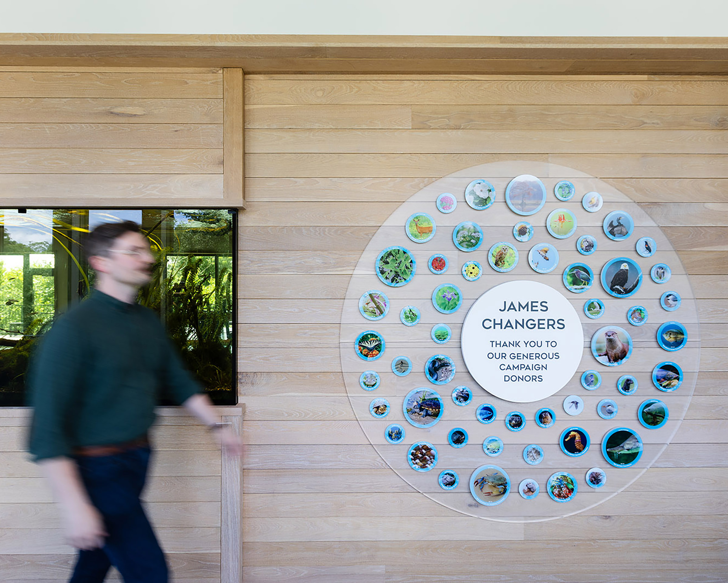 A man walks by the donor wall at JRA Buzzard River Education Center