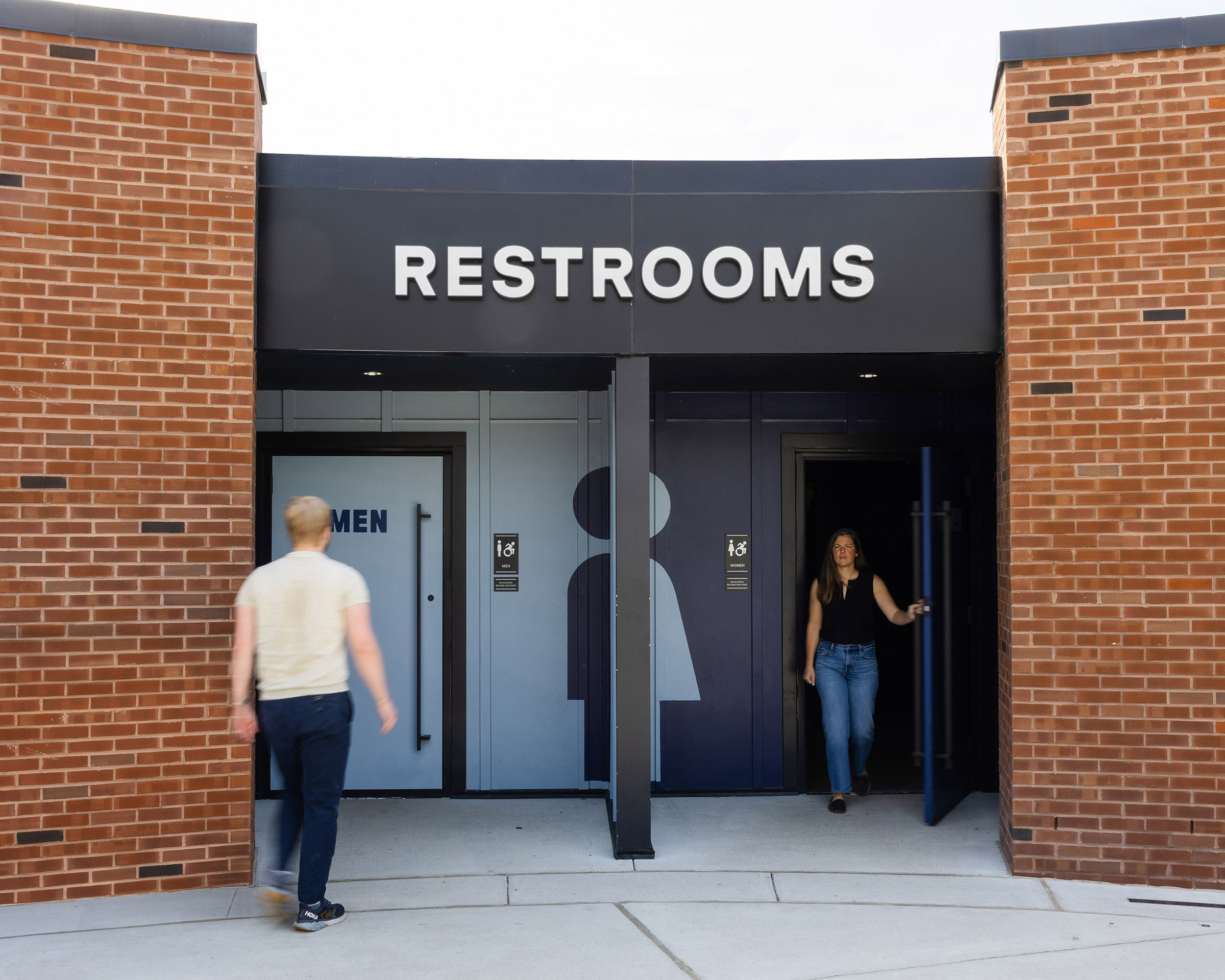 People enter and exit the restrooms at Allianz Amphitheater beside wall graphics