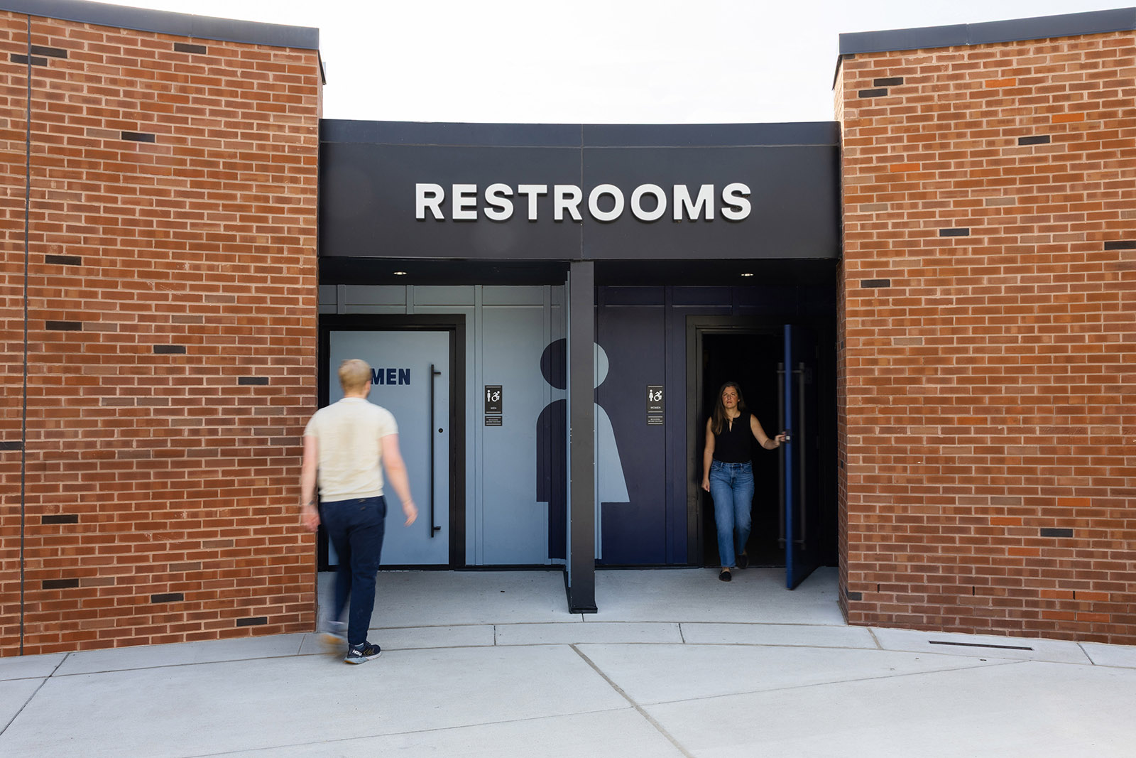 People enter and exit the restrooms at Allianz Amphitheater beside wall graphics