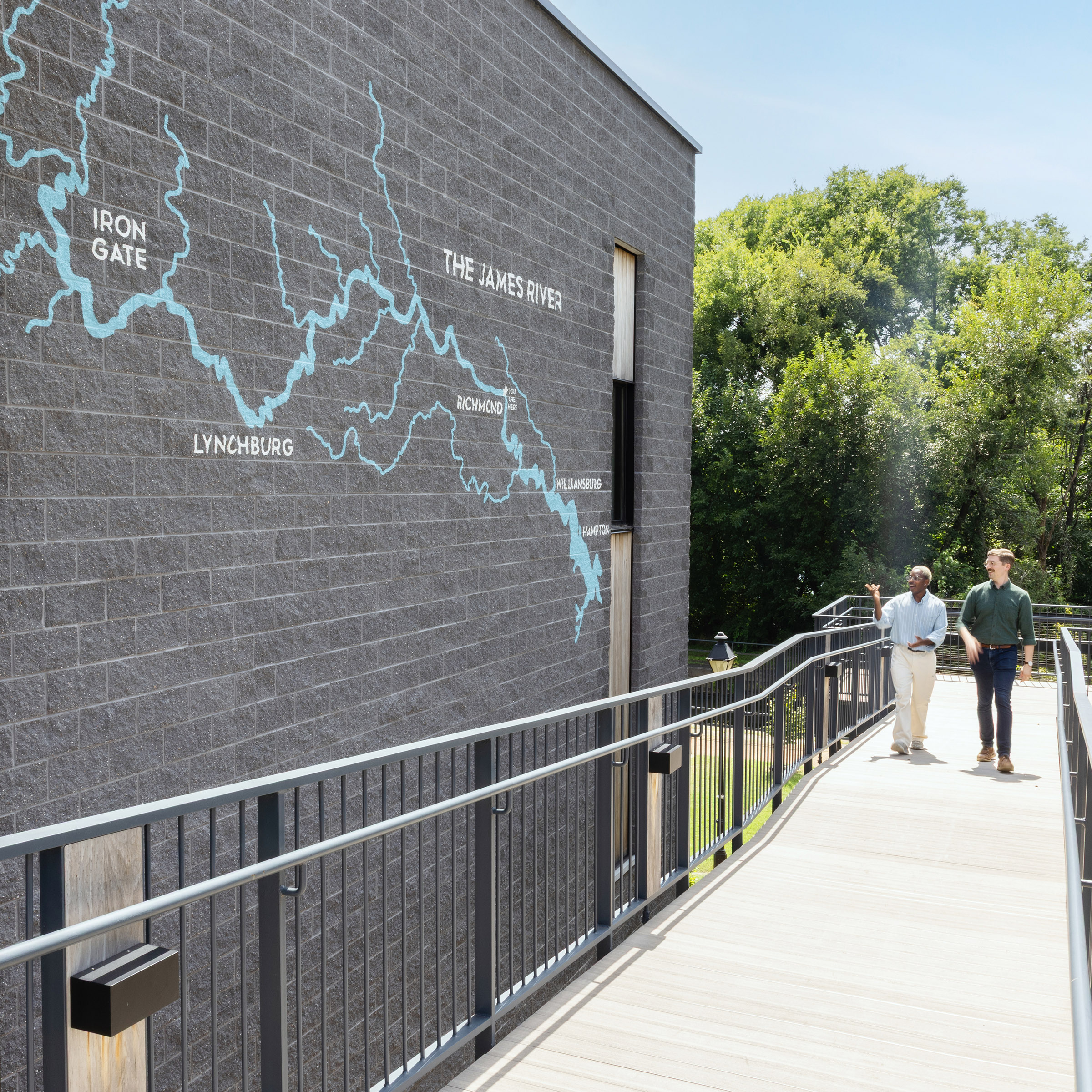Two men walk by outdoor painted wall graphics at JRA Buzzard River Education Center