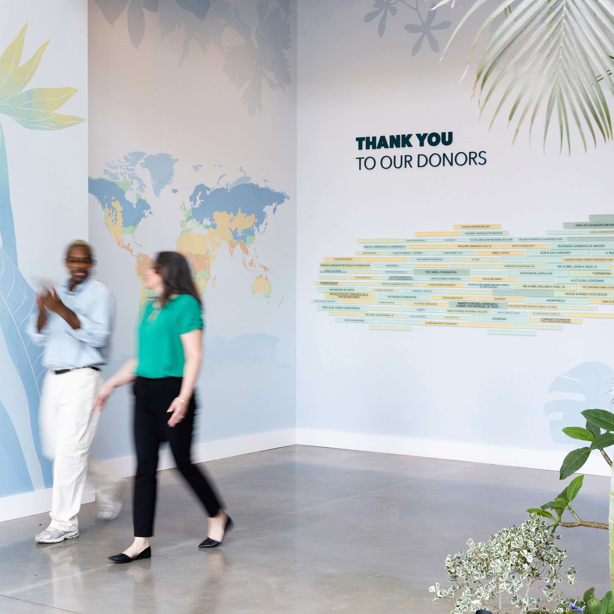 Two people walk by wall graphics and donor signage at Lewis Ginter Botanical Garden