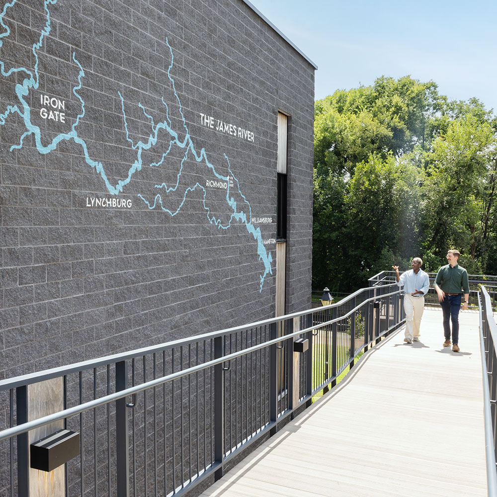 Two men walk by outdoor painted wall graphics at JRA Buzzard River Education Center