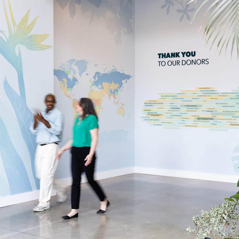 Two people walk by wall graphics and donor signage at Lewis Ginter Botanical Garden