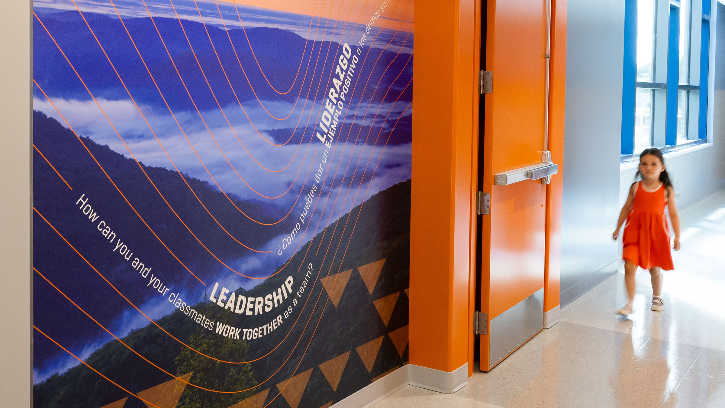 A child walks through a doorway at Mountain View Upper Elementary School with mountain wall graphics on the left side of the photo.