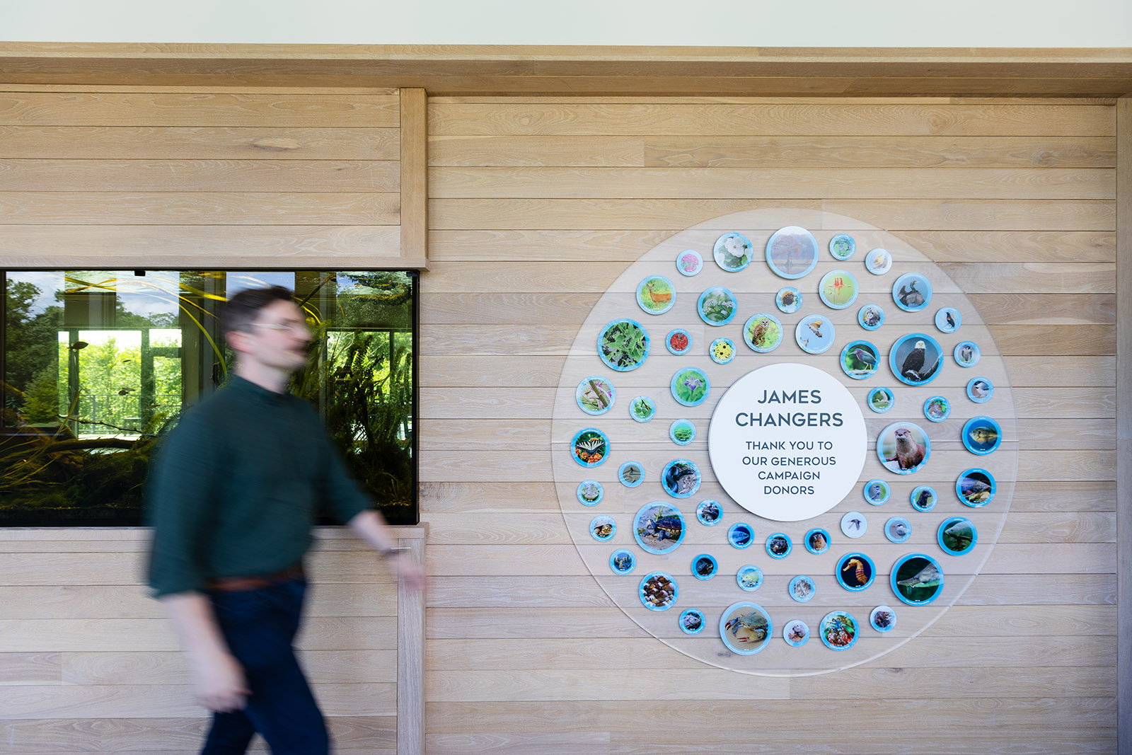 A man walks by the donor wall at JRA Buzzard River Education Center