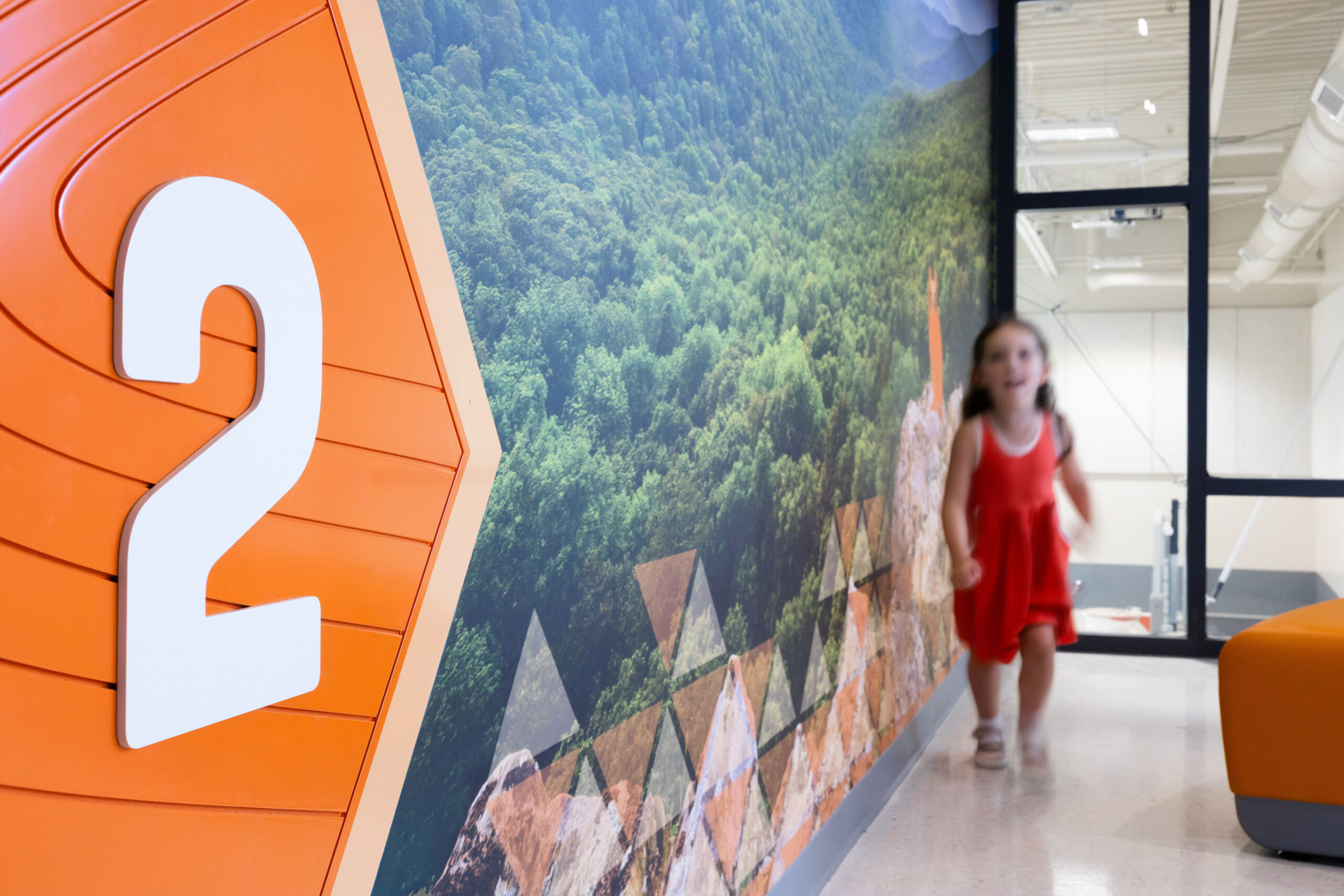 A child playing near mountain wall graphics at Mountain View Upper Elementary School featuring a dimensional floor number sign for level 2.